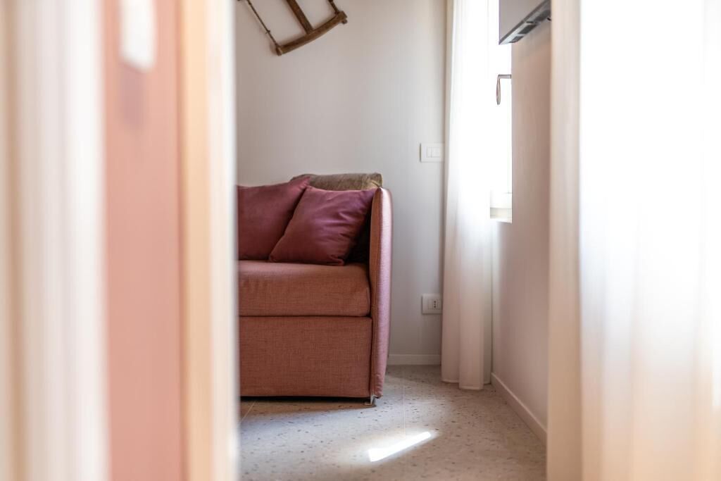 Ein enger Flur mit einem rosa Sofa und einer Holzleiter an der Wand.