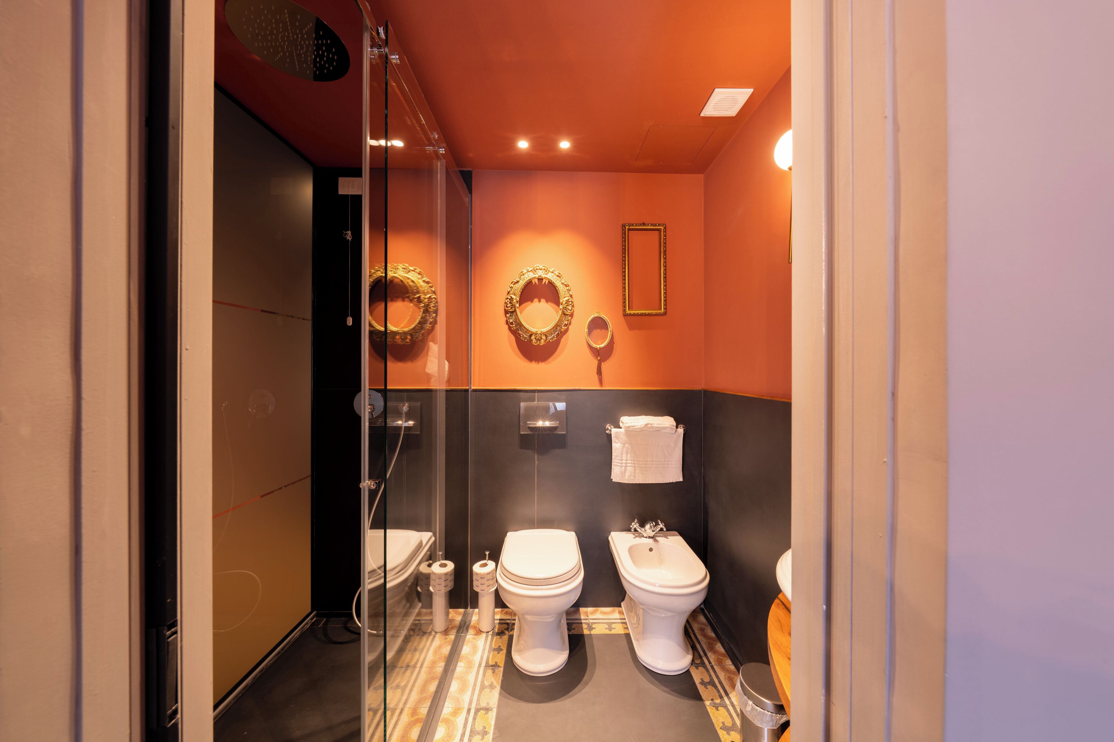 Baño con dos inodoros, ducha y mampara de vidrio.