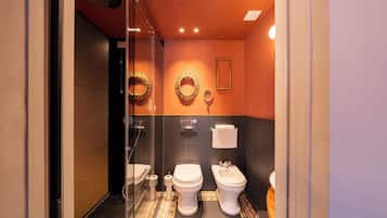 Baño con dos inodoros, ducha y mampara de vidrio.