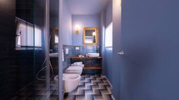 A modern bathroom with a glass shower enclosure, a white toilet, a bidet, and a sink with a mirror above.