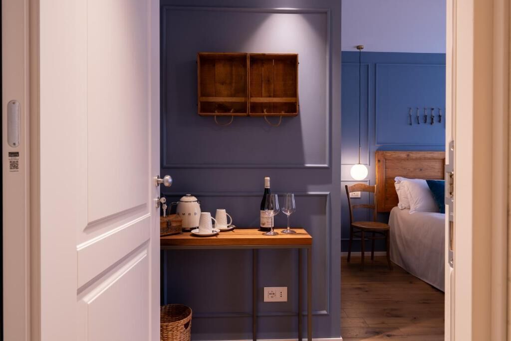 Una habitación con una mesa de madera, una cama, una pared azul y un estante colgante.
