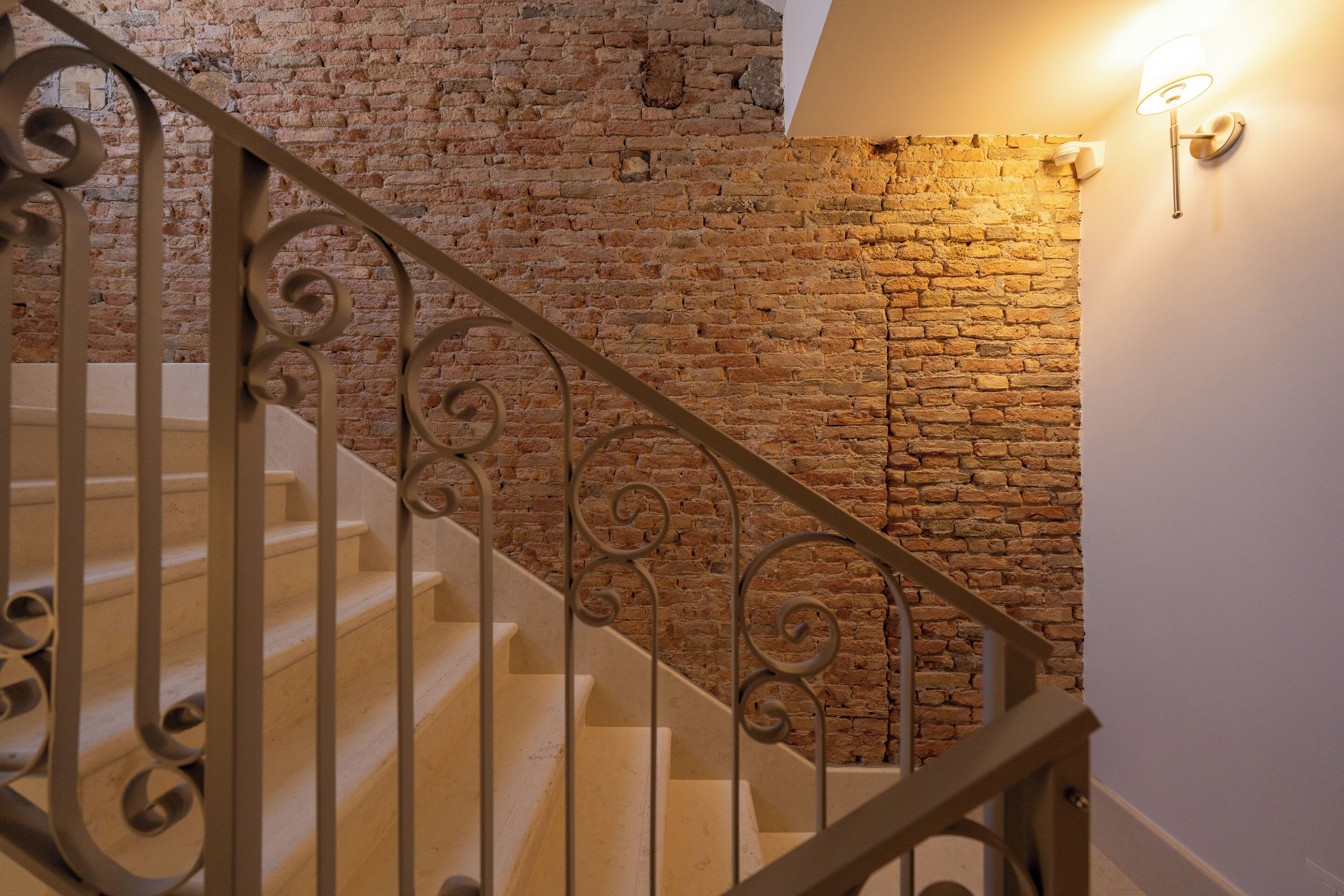 A staircase with ornate metal railings leading to a brick wall.