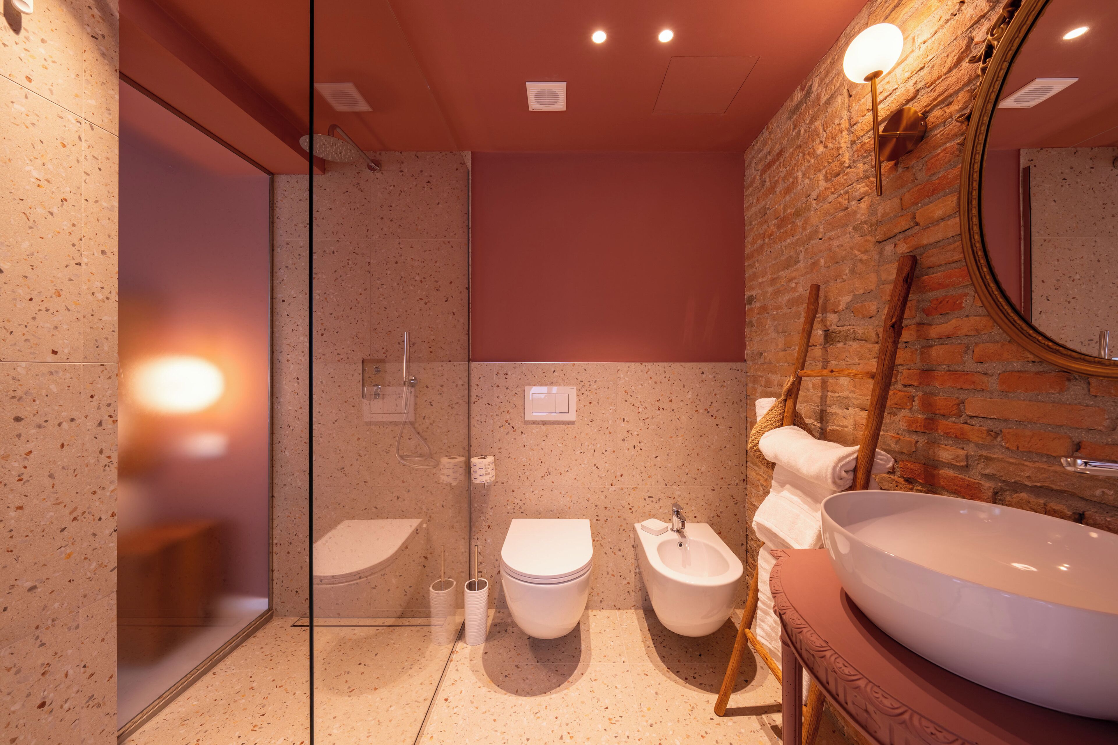 Un baño moderno con cabina de ducha de vidrio, inodoro independiente, bidé y un lavamanos grande con espejo.