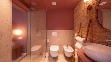 Un baño moderno con cabina de ducha de vidrio, inodoro independiente, bidé y un lavamanos grande con espejo.