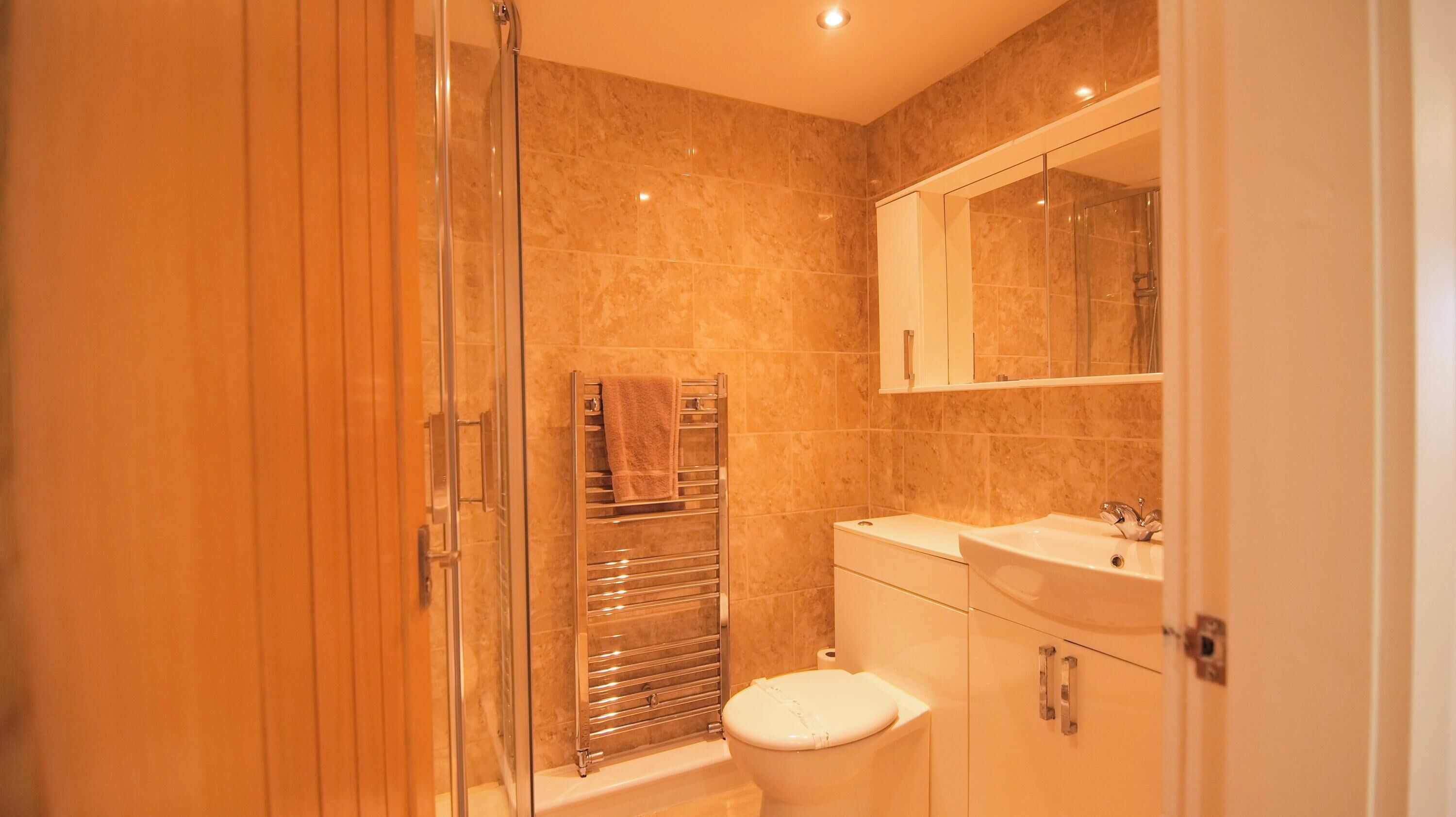A bathroom with a glass shower enclosure, a toilet, and a sink with a mirror above it.