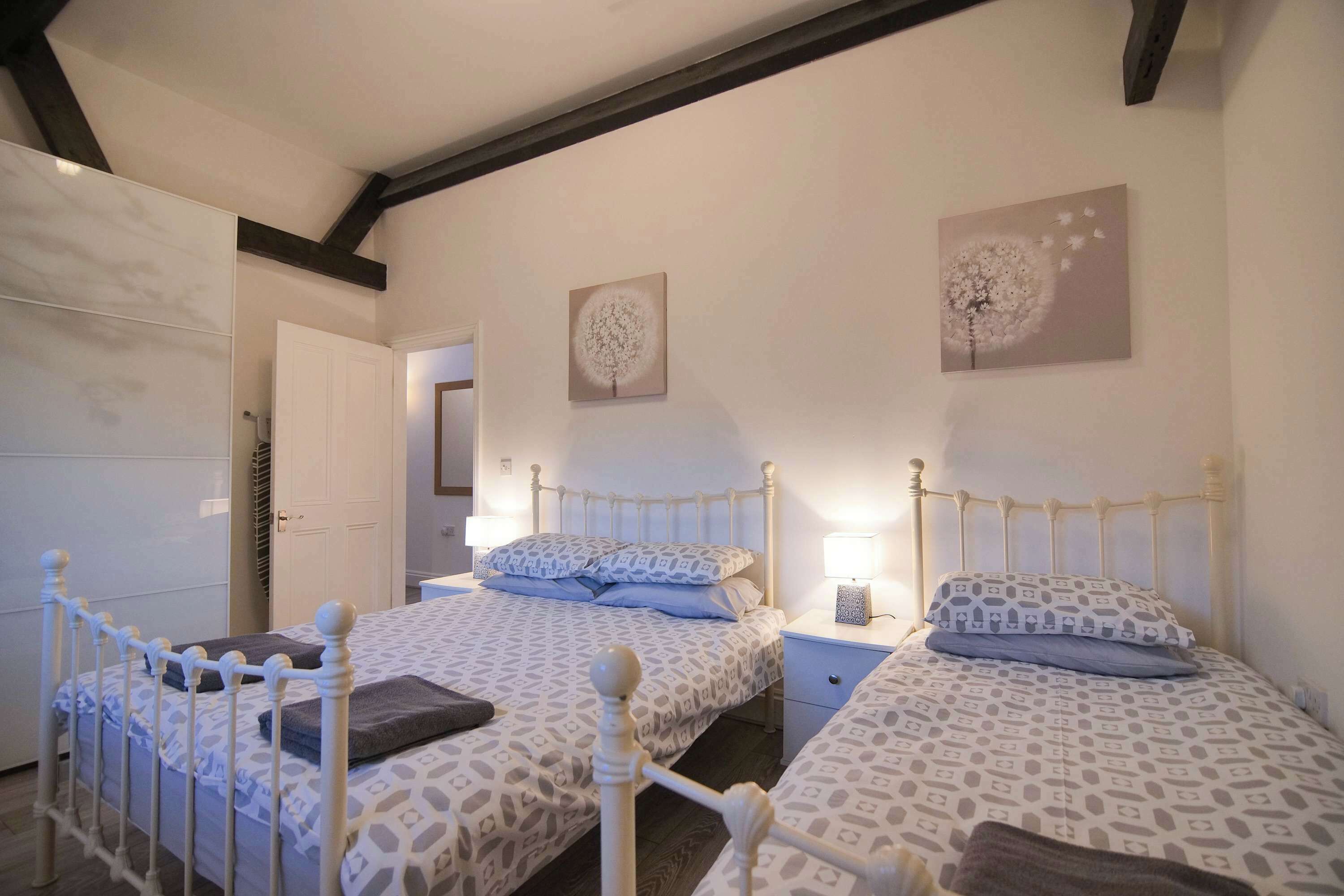 A bedroom with two beds, a wardrobe, and a door.