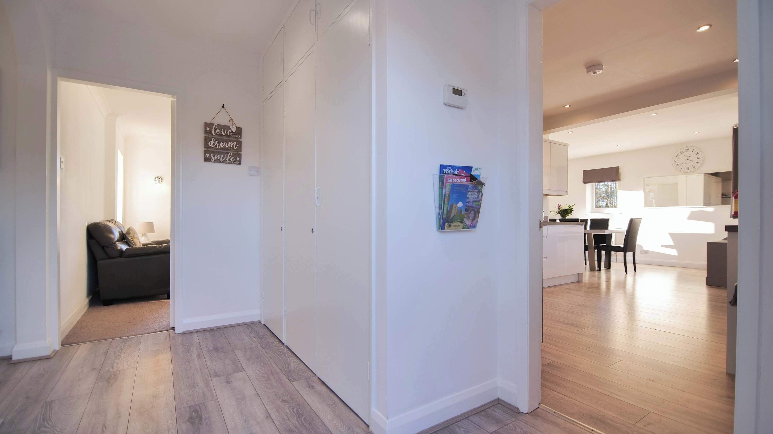 A modern interior with a sofa, a wall-mounted sign, a bulletin board, and a kitchen area.