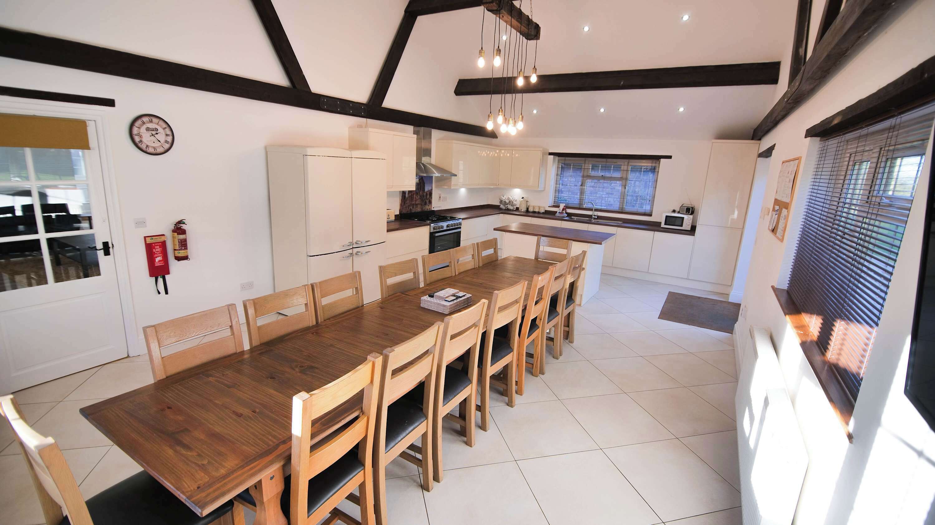 A modern kitchen with white cabinets, a wooden dining table, and a built-in oven.