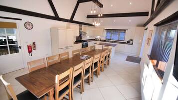 A modern kitchen with white cabinets, a wooden dining table, and a built-in oven.