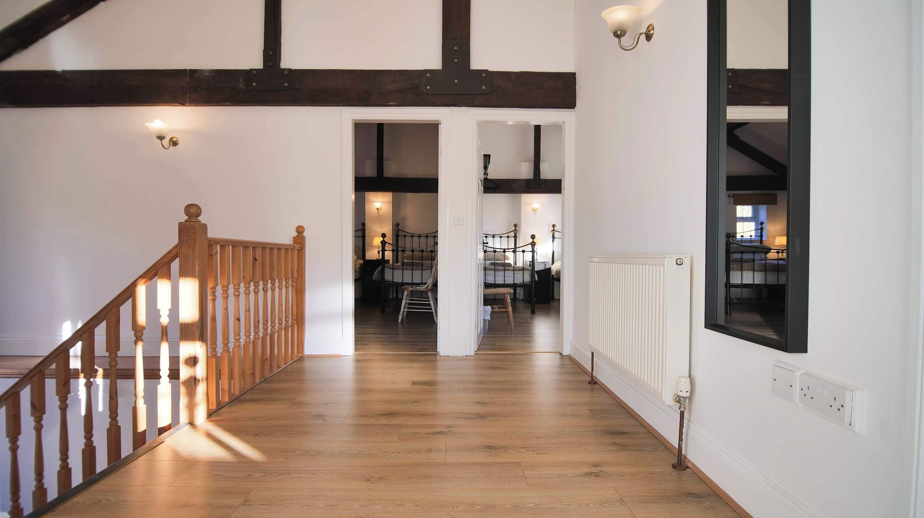 A hallway with wooden flooring, a wooden staircase, and a white radiator.
