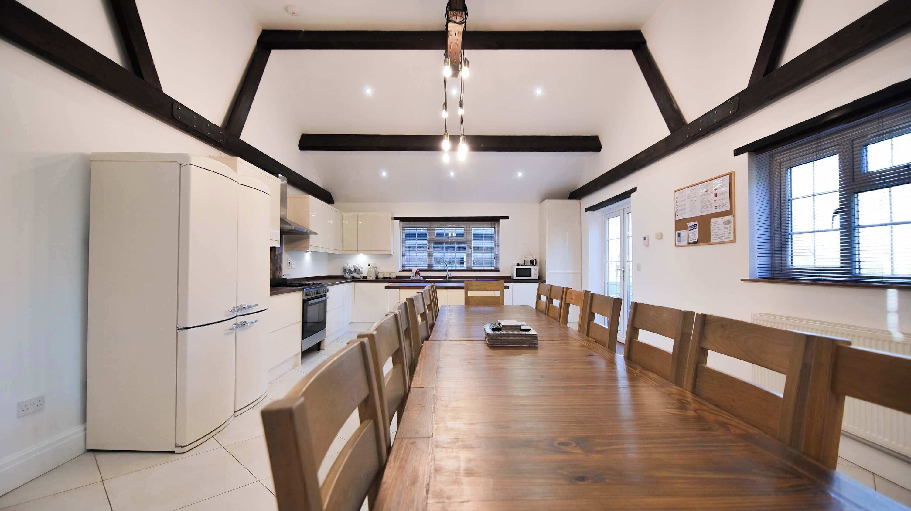 A modern kitchen with a central island, wooden dining table, and built-in appliances.