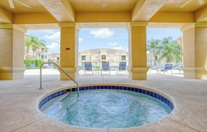 A hot tub area with a view of a building and palm trees. - Pink Apple l Modern Comfort (Davenport)