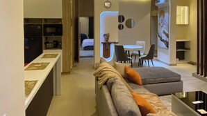 Una sala moderna con un sofá, un comedor y una cocina visible al fondo.