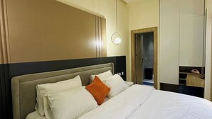 Una habitación de hotel con una cama grande, una mesita de noche, un armario y un espejo.