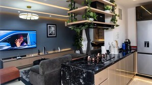 Una cocina moderna con encimera de mármol, electrodomésticos integrados y televisor montado en la pared.