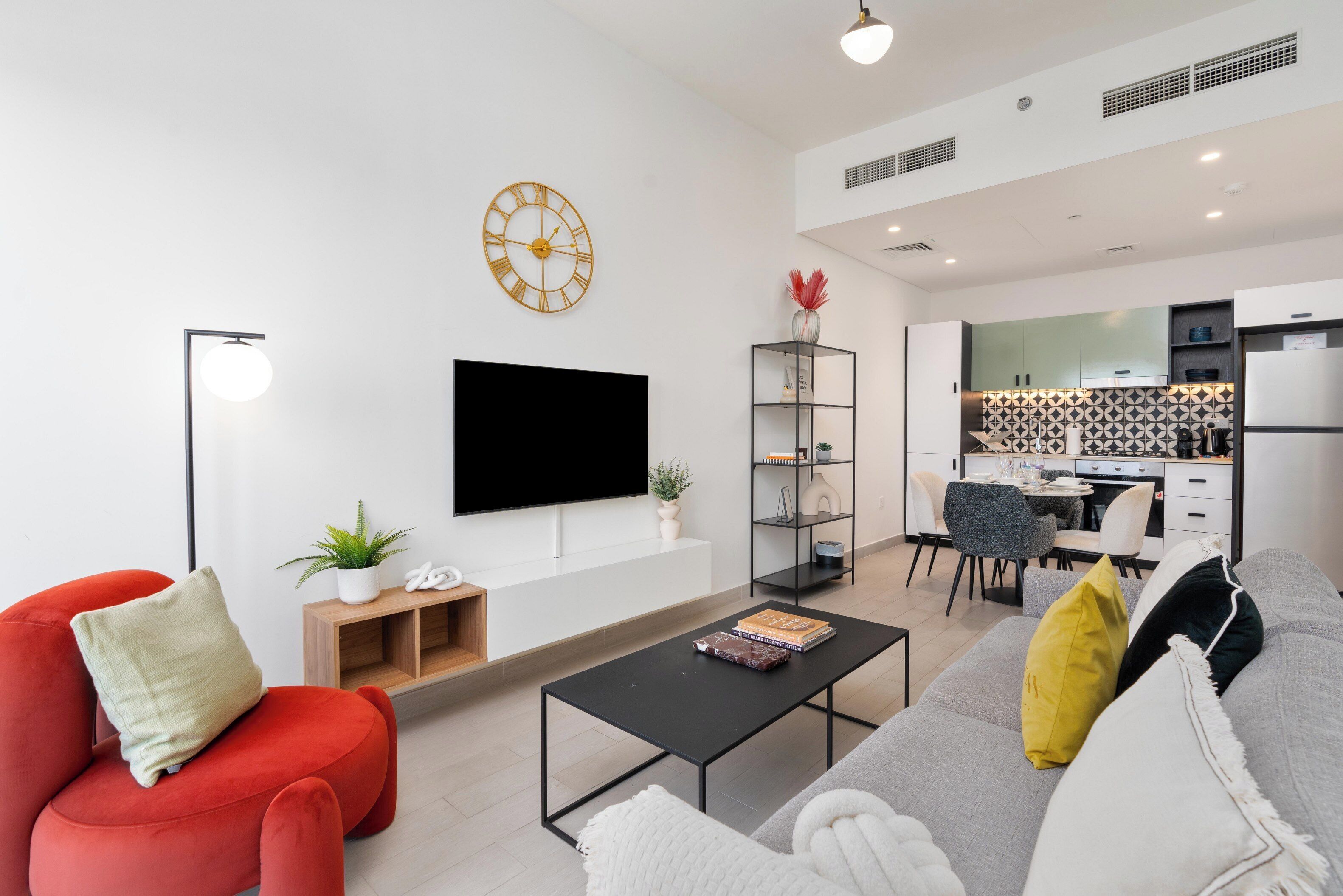 Una sala moderna con una televisión de pantalla plana, un sofá rojo, un sofá gris, una mesa de centro y una estantería.