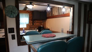 Una cucina compatta con tavolo, sedie e un orologio appeso al muro.