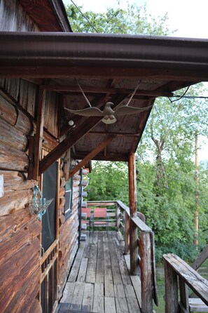 A wooden cabin with a porch, a ceiling fan, and a view of the surrounding forest. - The Eagle Cabin - Mountaintop Ranch (Elkton)