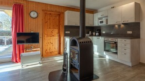 A modern kitchen with a wood stove, a microwave, and a clock on the wall. - Familienfreundlicher Doppelbungalow mit Terrasse im Ferienpark Mirow (Mirow)