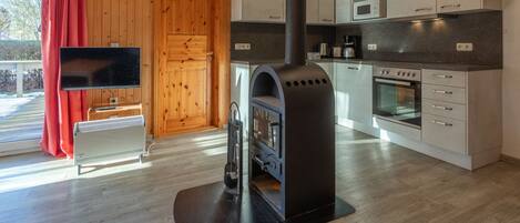 A modern kitchen with a wood stove, a microwave, and a clock on the wall.