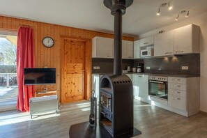 Eine moderne Küche mit Holzofen, Mikrowelle und einer Uhr an der Wand.