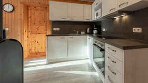 A modern kitchen with wooden paneling, a built-in oven, and a microwave. - Familienfreundlicher Doppelbungalow mit Terrasse im Ferienpark Mirow (Mirow)