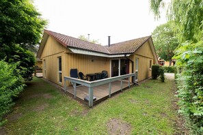 Eine Holzhütte mit Ziegeldach, einer Terrasse und einer Sitzgelegenheit im Freien mit Gartenmöbeln.