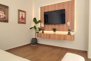 A modern room with a mounted TV, wooden panel wall, potted plants, and a small shelf. - Recoleta Studio with Balcony • Couples, remote workers, business travelers (Asunción)