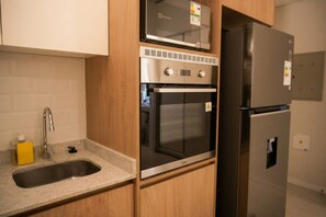 Eine Küche mit einem Edelstahl-Kühlschrank, Backofen und einer Mikrowelle.