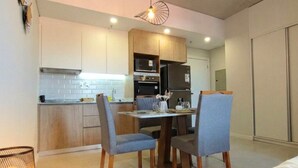Una cocina moderna con armarios de madera, una mesa de comedor con sillas y una cama en primer plano.