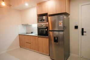 Une cuisine moderne avec des meubles en bois, un réfrigérateur en acier inoxydable, un four et un four à micro-ondes.