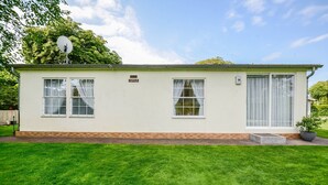 A single-story building with a flat roof, two windows on the front, and a satellite dish on the roof. - Rauchfangswerder Holiday Home with Private Terrace, Garden, and Wi-Fi (Berlin)
