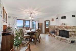 A spacious living area with a fireplace, dining table, and chairs. - Nasdala Holiday Apartment: Relax with Stunning Panoramic Views (Bühlertal)