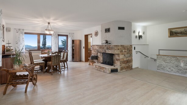 A spacious living area with a fireplace, dining table, and chairs.