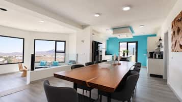 Un comedor moderno con una mesa larga, varias sillas y vistas del paisaje a través de ventanas amplias.