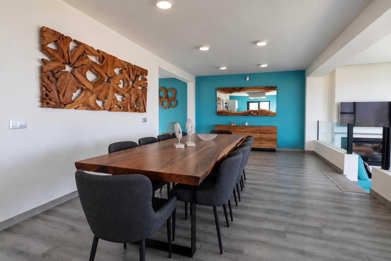 Een moderne eethoek met een houten tafel en stoelen, een decoratief muurkunstwerk en uitzicht op de keuken.