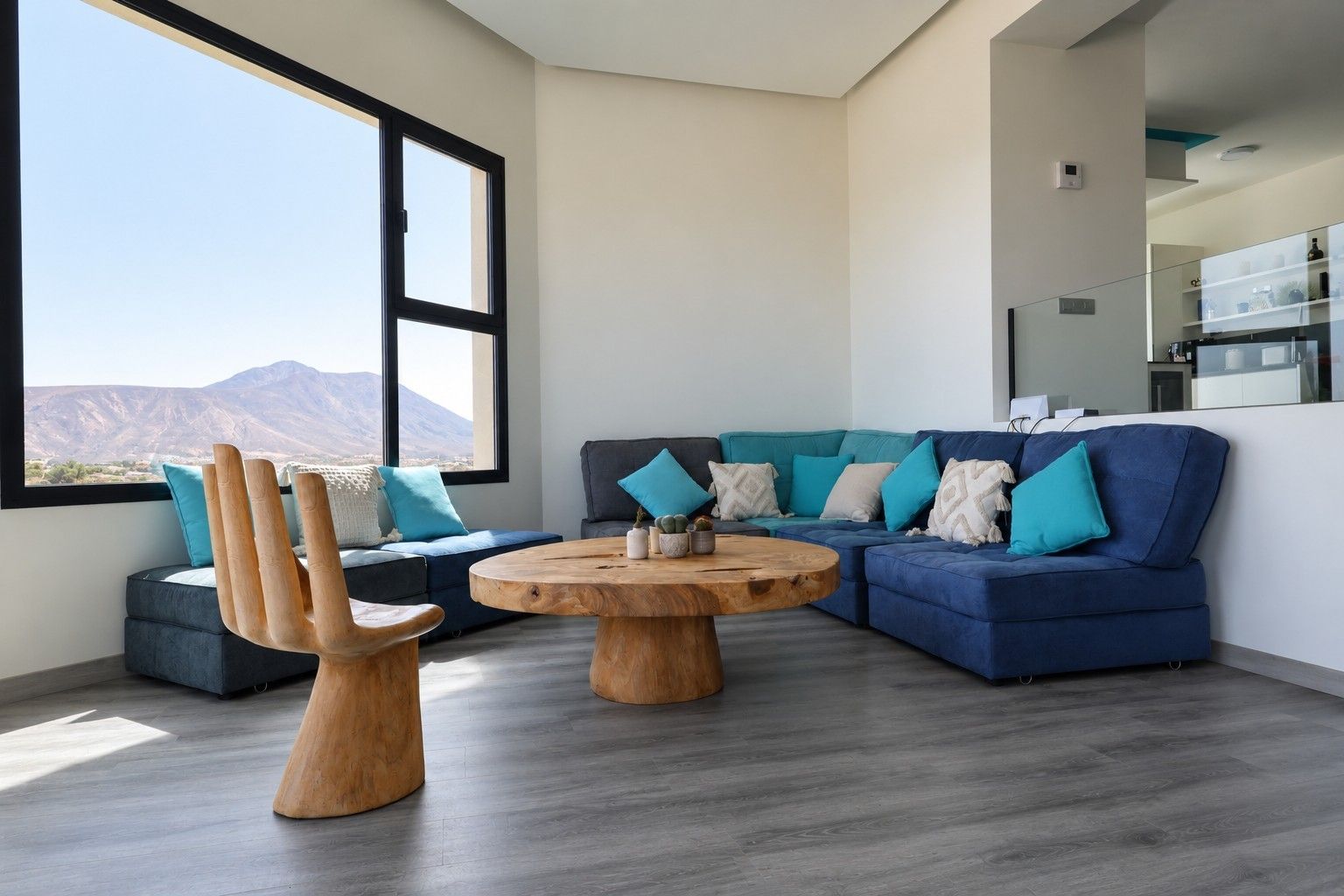 Una sala de estar moderna con un ventanal grande, un sofá azul, una mesa de centro de madera y un diseño de silla original.
