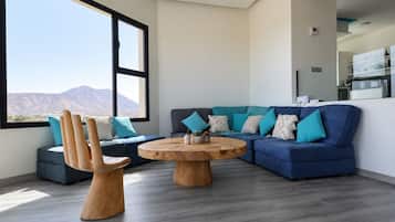 Una sala de estar moderna con un ventanal grande, un sofá azul, una mesa de centro de madera y un diseño de silla original.
