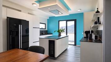 Cocina moderna con isla central, muebles blancos, refrigerador negro y pared de acento azul.