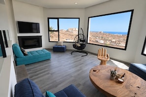 A modern living room with a large window, a sofa, a hanging chair, and a wooden coffee table. - Vacation villa 'Exceptionnelle avec piscine' with sea view, private pool and Wi-Fi (Villaverde)