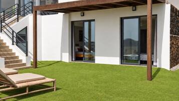Et moderne hus med en overdækket terrasse, en trappe og en velplejet græsplæne.