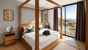 A four-poster bed with a view of a coastal landscape.