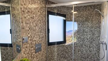 Een moderne badkamer met een grote spiegel, een wastafel en een douche met uitzicht op de omgeving.