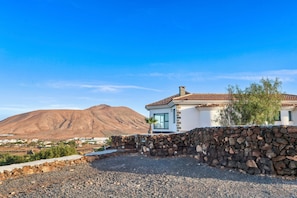A house with a stone wall, a mountain in the background, and a clear sky. - Vacation villa 'Exceptionnelle avec piscine' with sea view, private pool and Wi-Fi (Villaverde)