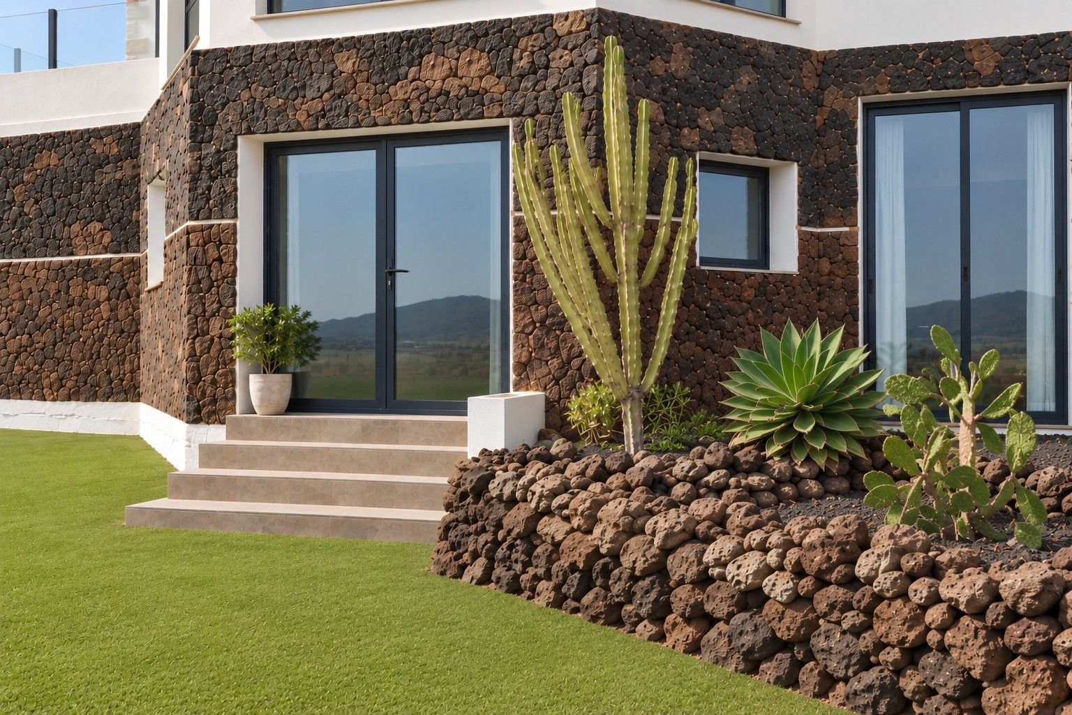 Un edificio moderno con fachada de piedra, amplias ventanas y un césped cuidado.