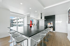 A modern kitchen with a large island, bar stools, and a view of the city. - Spacious Apartment with a View of Paris (Puteaux)