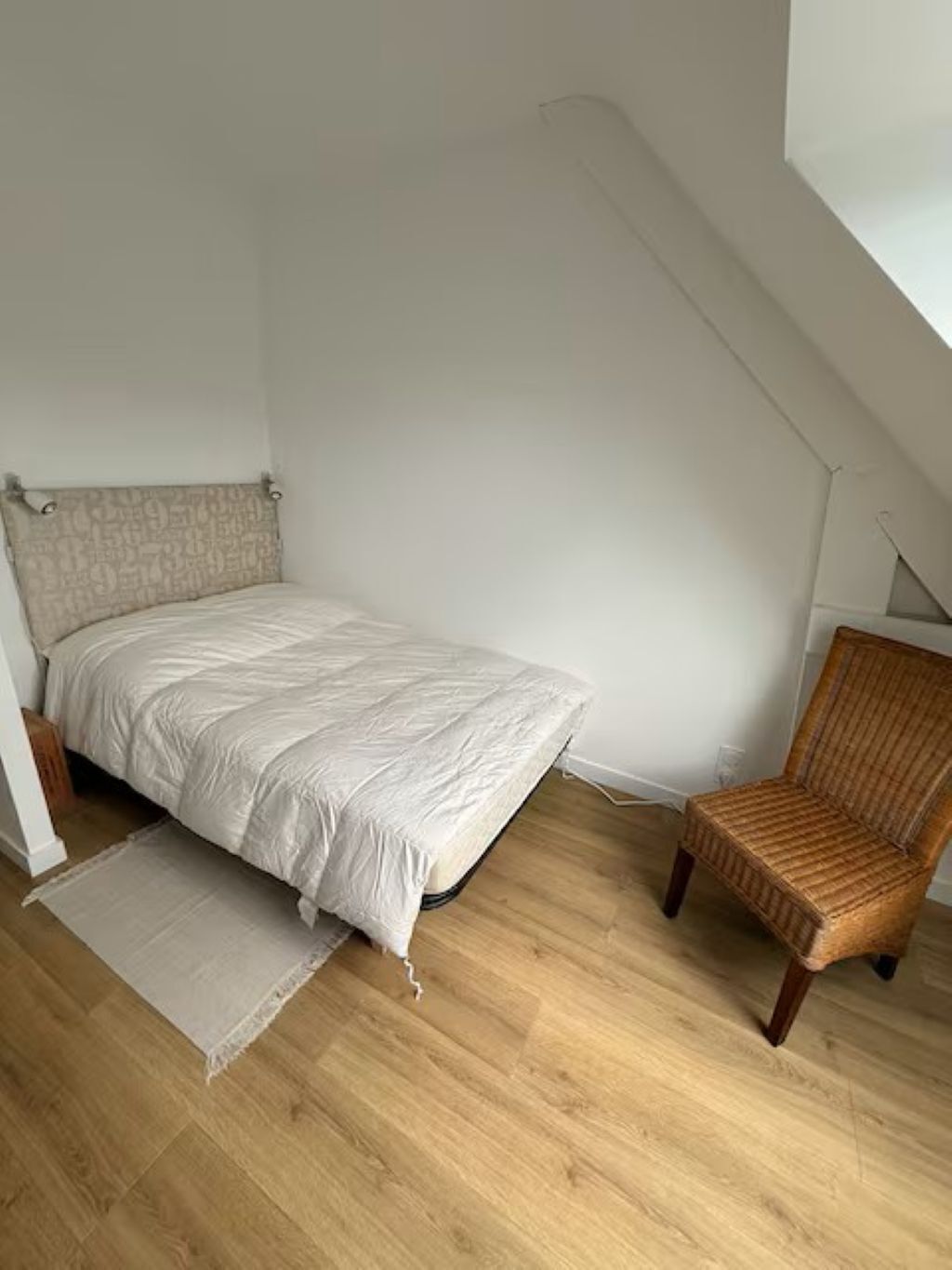 Une chambre à coucher avec un lit, une chaise et un plancher en bois.