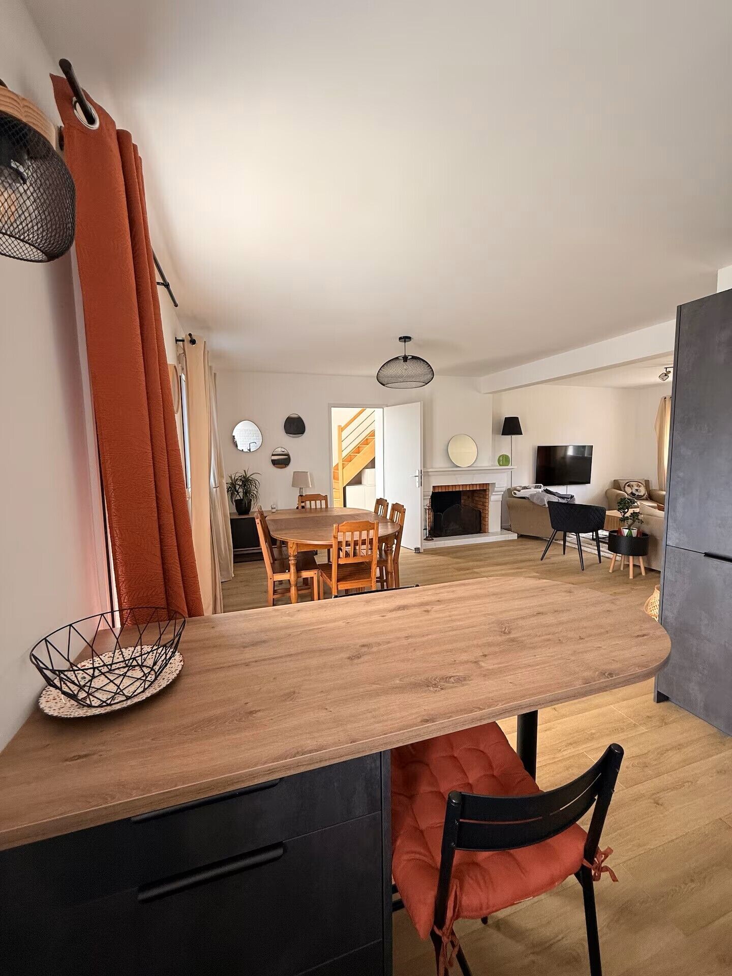 Una cocina moderna con encimera de madera, comedor con mesa y sillas, y sala de estar con sofá y televisor.
