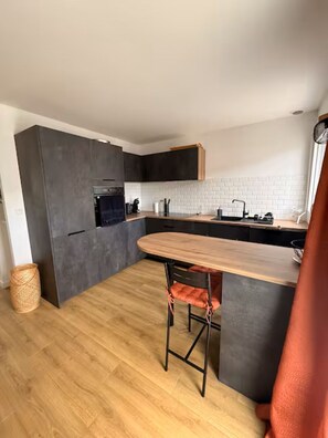 A modern kitchen with dark cabinets, a wooden countertop, and a built-in oven. - Single-family home near amenities (Arzon)