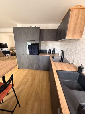 Eine moderne Küche mit grauen Schränken, einer Holz Arbeitsplatte und einem eingebauten Ofen.